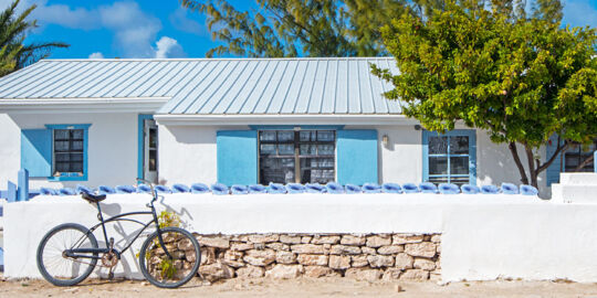 Quaint white and blue house with a bicycle in front on Salt Cay.